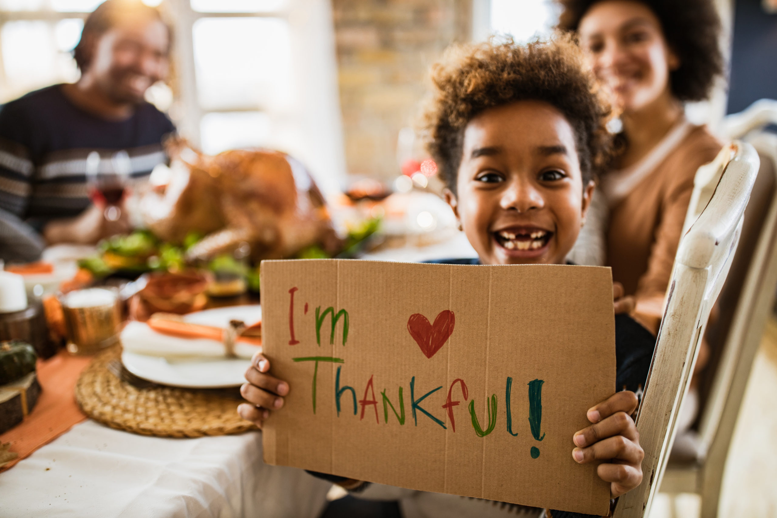 Happy African American girl holding 'I'm thankful' sign and ...
