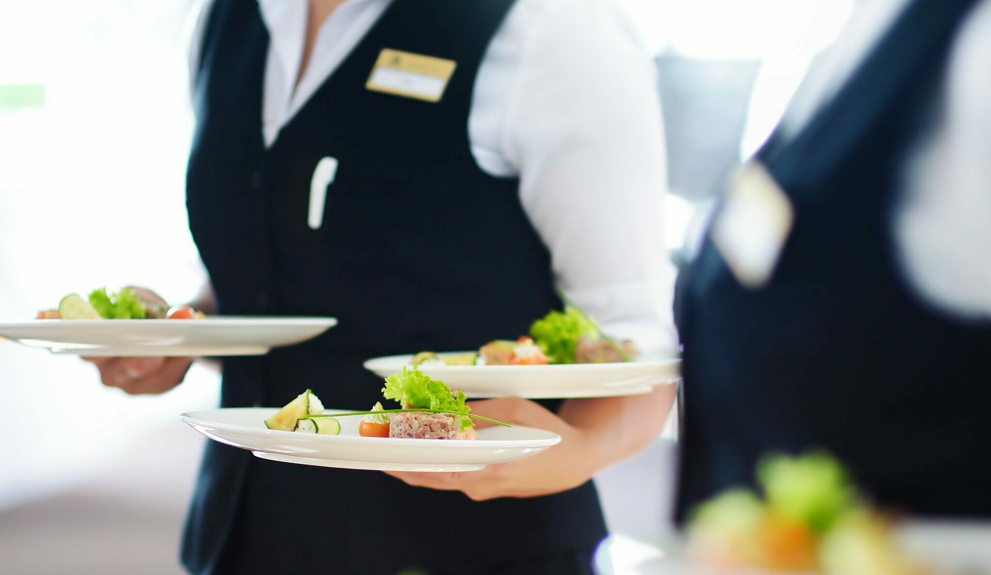 Waiter carrying plates with meat dish on some festive event, party or wedding reception